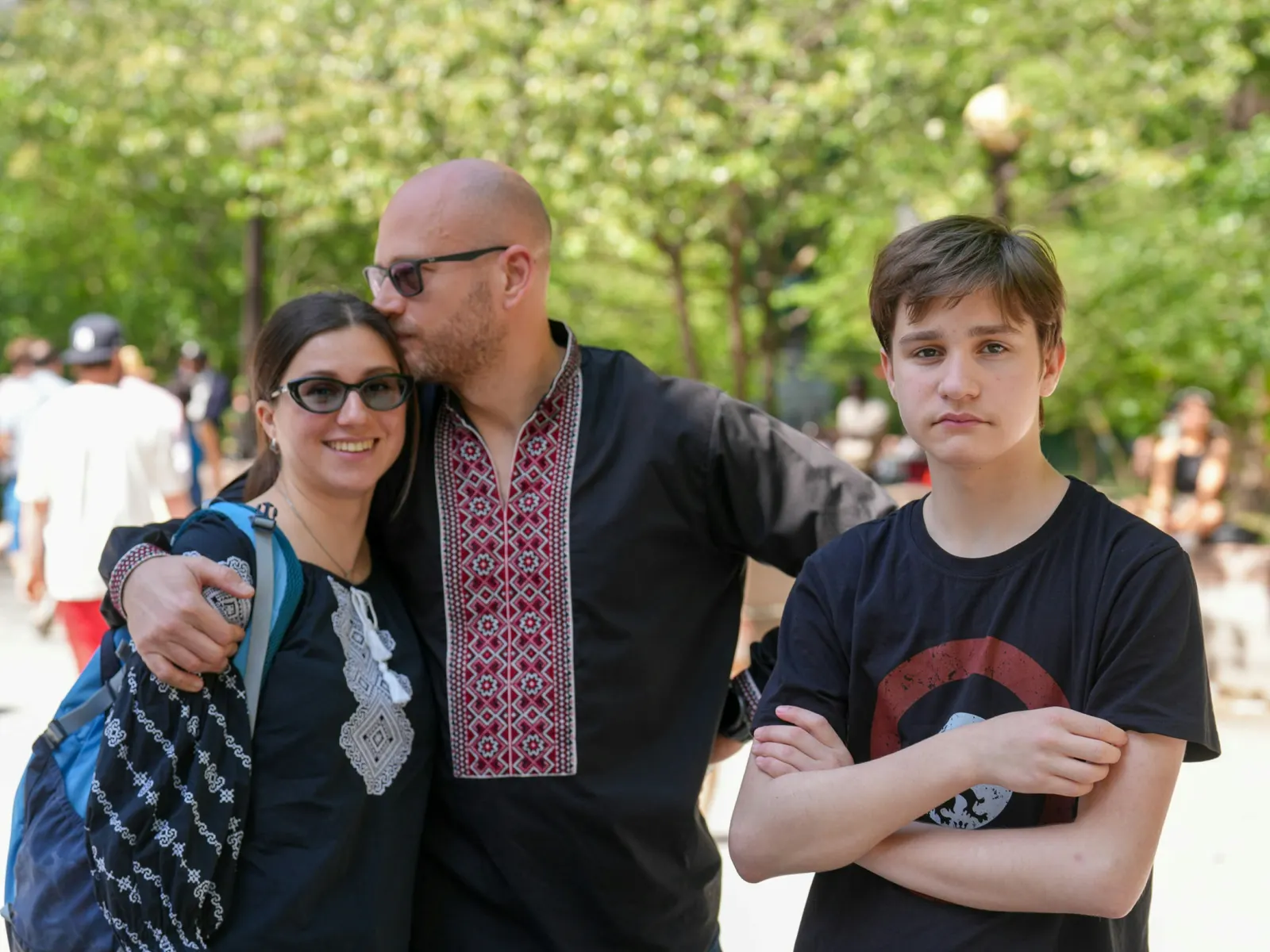 Parents and their teenage son smiling together in a city park
